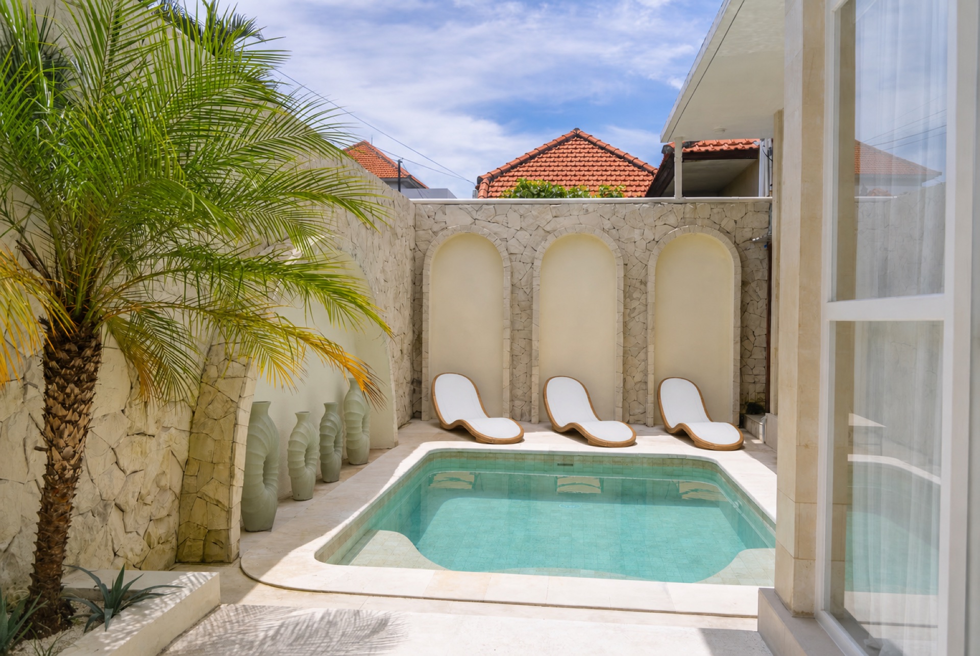Palm trees beside a sunlit pool at Villa Lysa, Bali